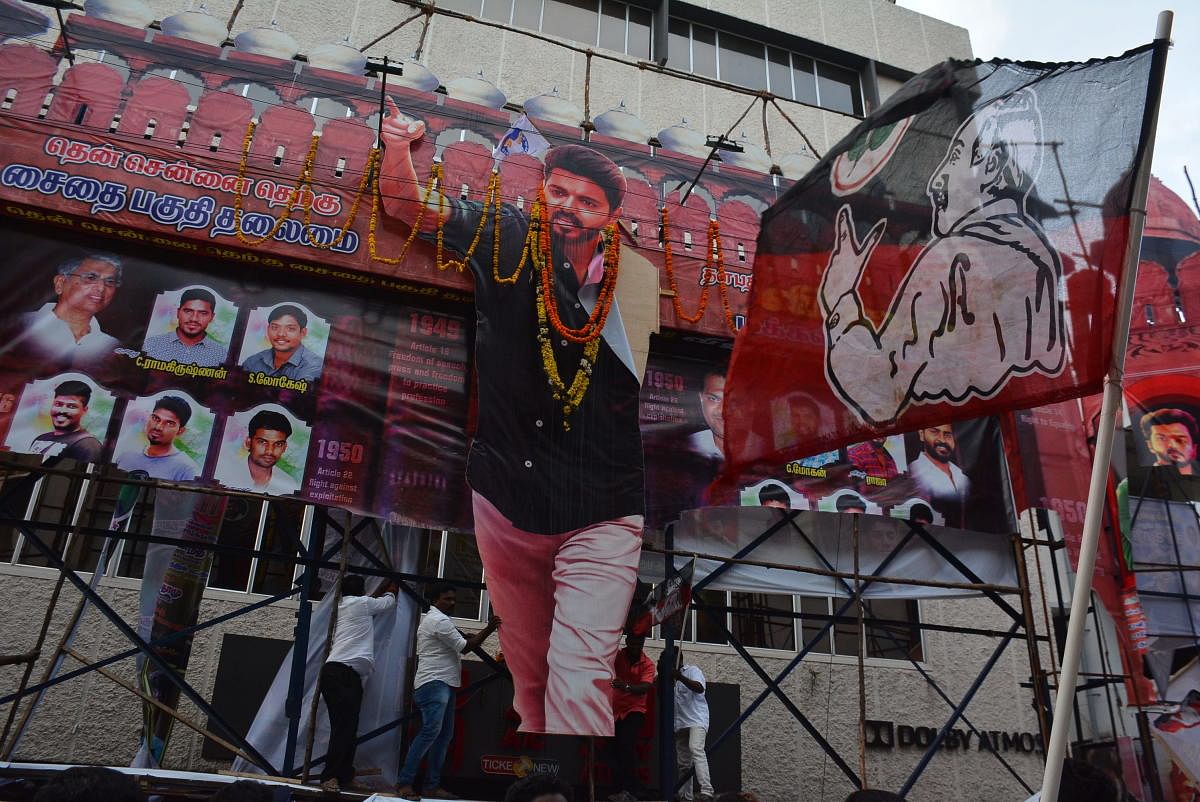 AIADMK cadre tearing the banner of actor Vijay's Sarkar at Kasi Theatre in Chennai. DH photo