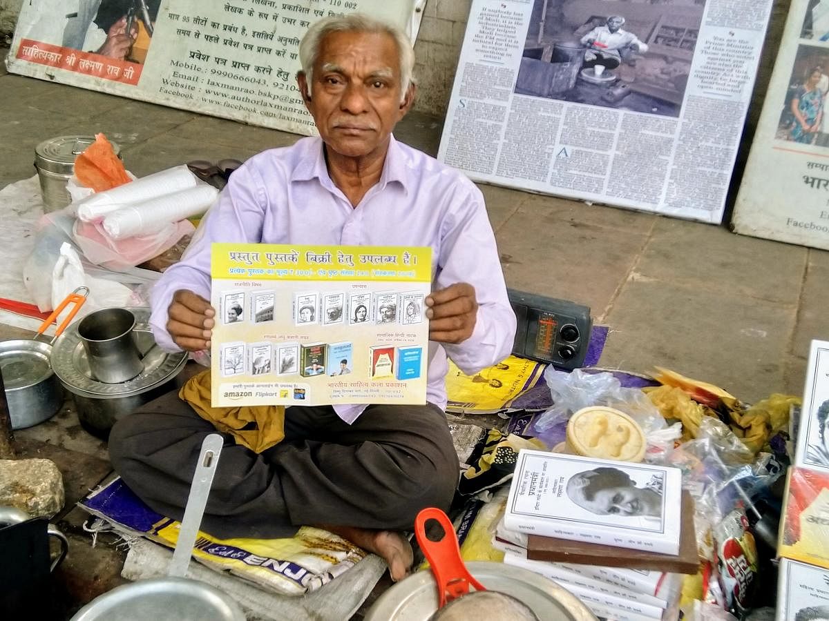Words and vocation: Laxman Rao holds a self-published book at his tea stall in Delhi.