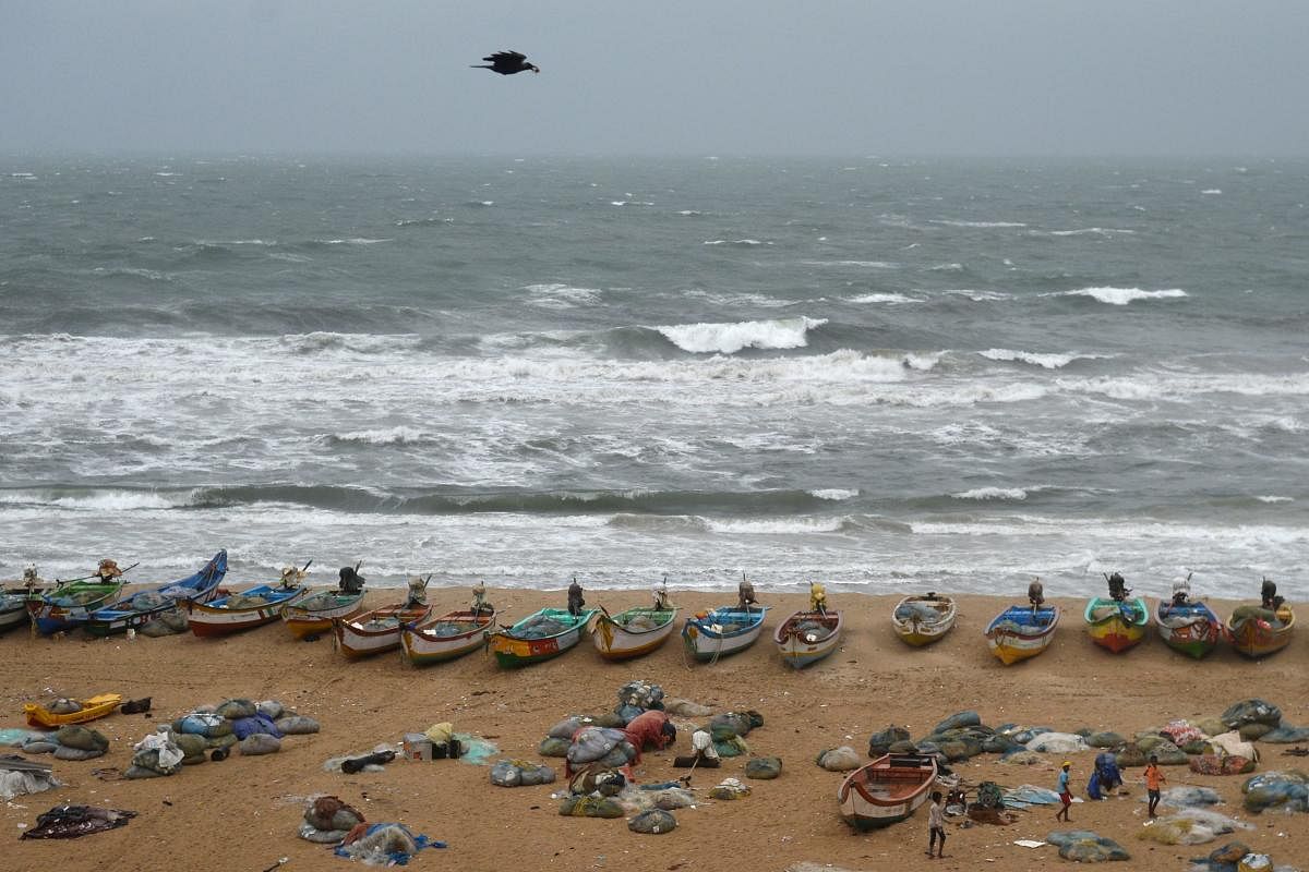 Fishing boats are seen on shore as waves pound the coast during rainy weather at Pattinapakkam beach in Chennai on Wednesday. AFP
