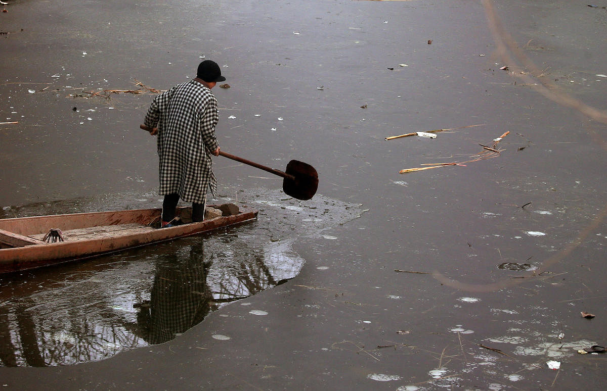 A boy uses his oar to break ice to move his boat on the frozen Anchar Lake on a cold winter day in Srinagar December 27, 2018. (REUTERS)