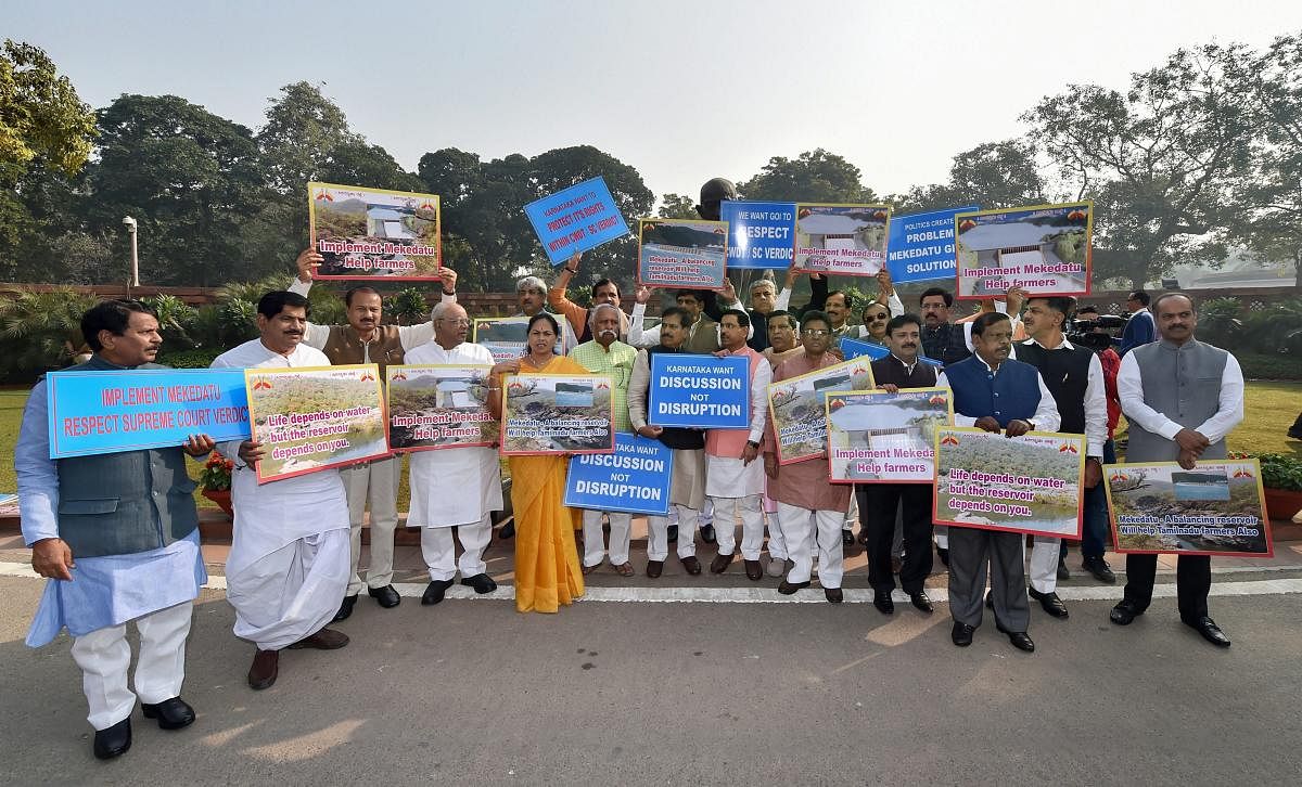 Karnataka MPs hold placards during a protest over the Mekedatu dam project in front of the Gandhi statue during the Winter Session of Parliament, in New Delhi on Thursday.