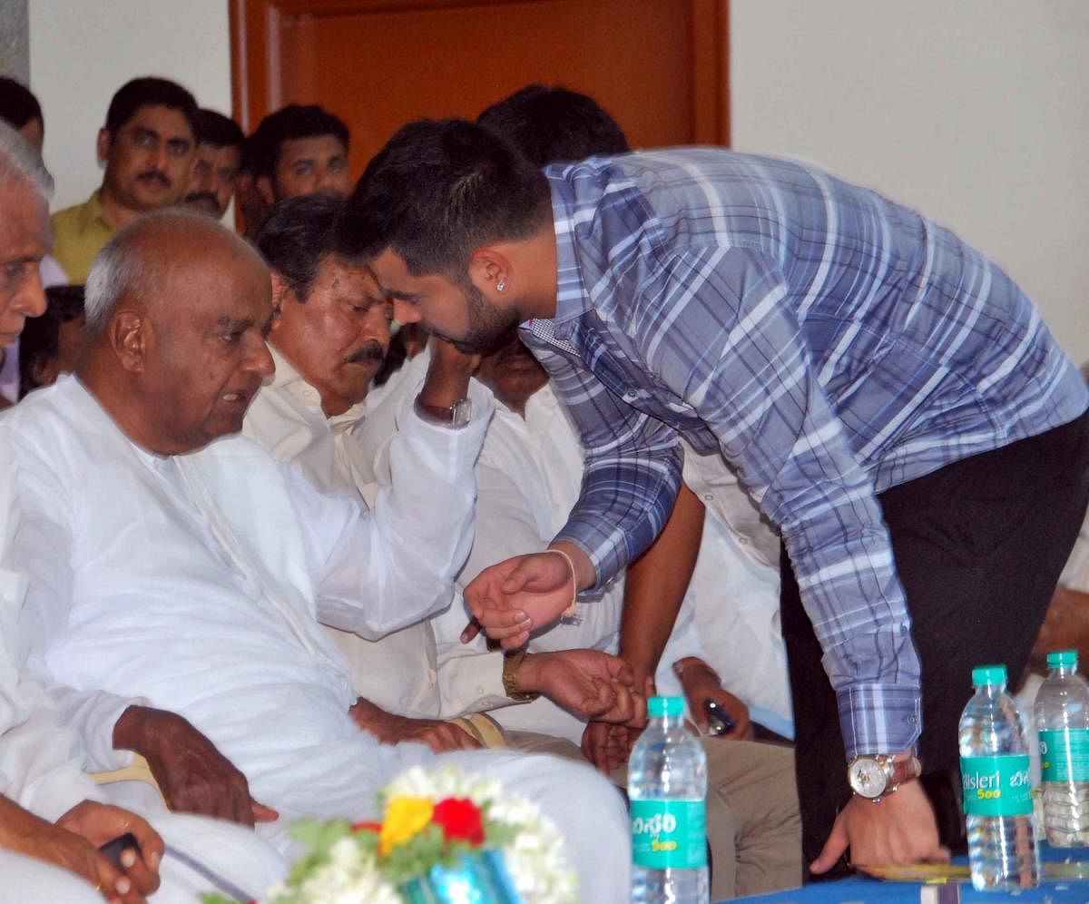 JD(S) supremo H D Deve Gowda talks to his grandson Prajwal Revanna during a party workers' meeting in Hassan on Sunday. DH PHOTO