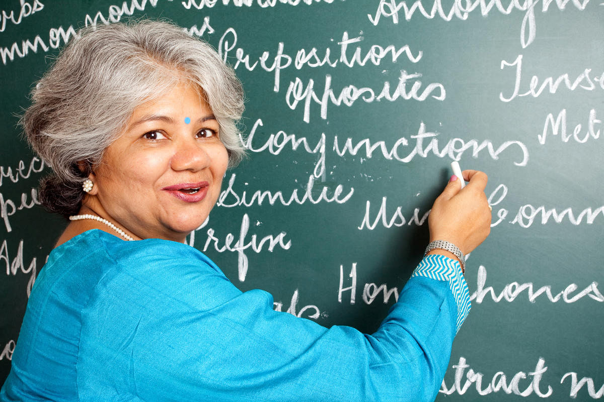 Cheerful Indian Woman English Teacher in Classroom with greenboard interacting with classWoman - Business _ Teacher