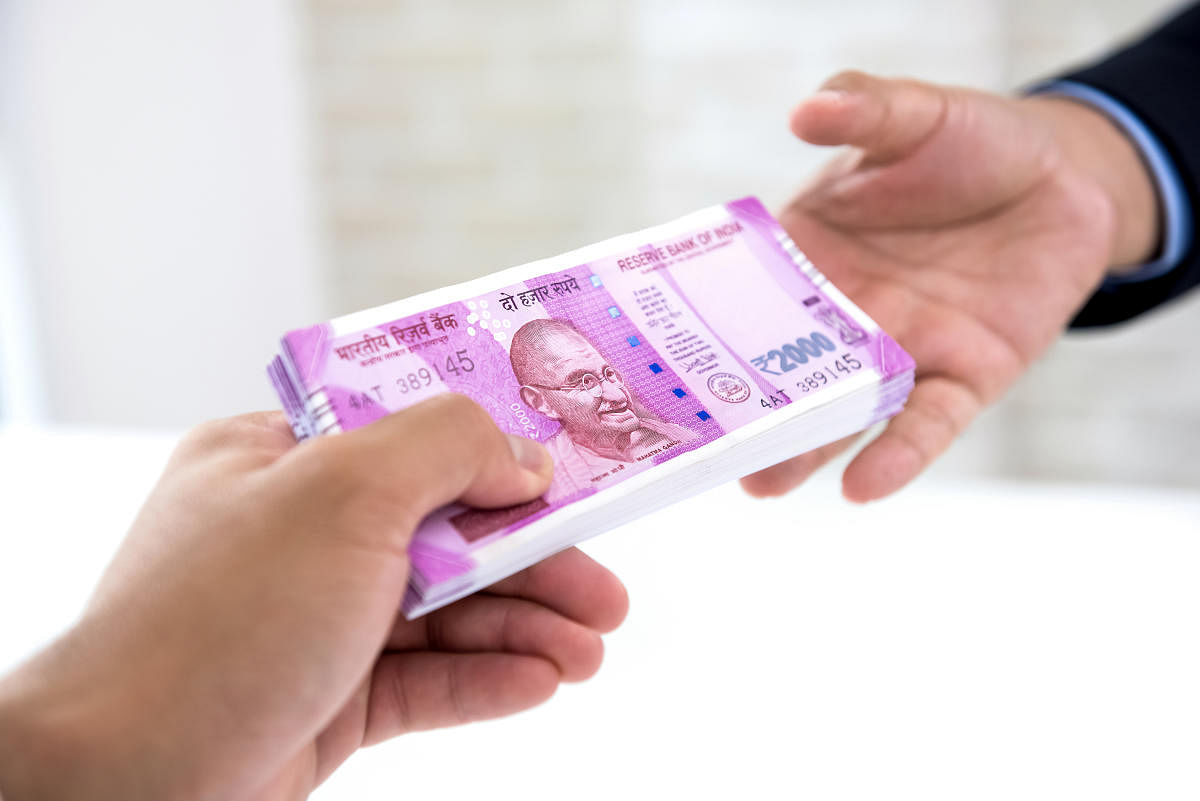 Businessman handing over wad of crisp new Indian rupee banknote money to his partner. (iStockPhotos)