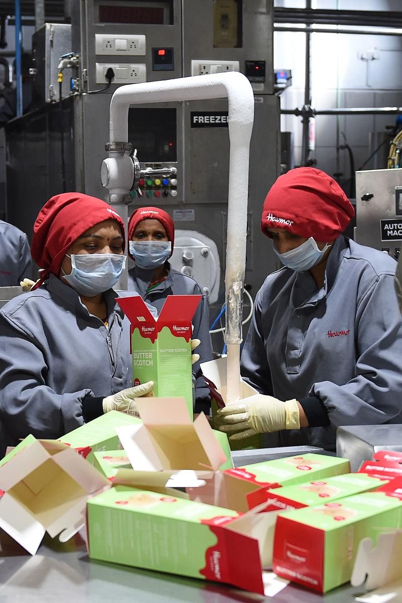Indian factory workers fill packs of ice creams on an assembly line at the Havmor Ice Cream plant in Naroda, some 18 km from Ahmedabad, on April 4, 2019. - South Korea's Lotte Confectionery Group in 2017 took over India's Havmor Ice Cream, which produces