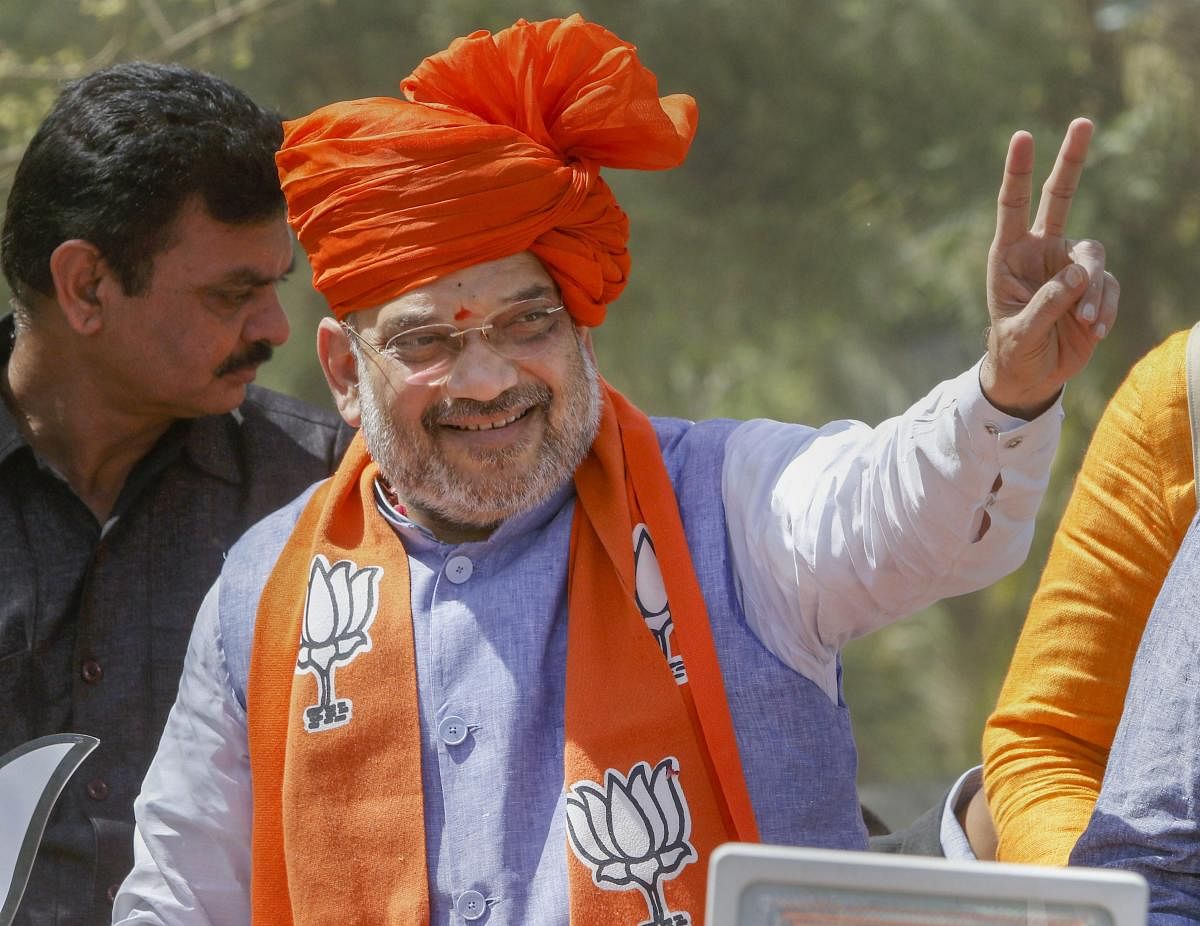 BJP President Amit Shah flashes victory sign during an election campaign roadshow, ahead of the general elections-2019, in Ahmedabad, April 6, 2019. (PTI Photo)