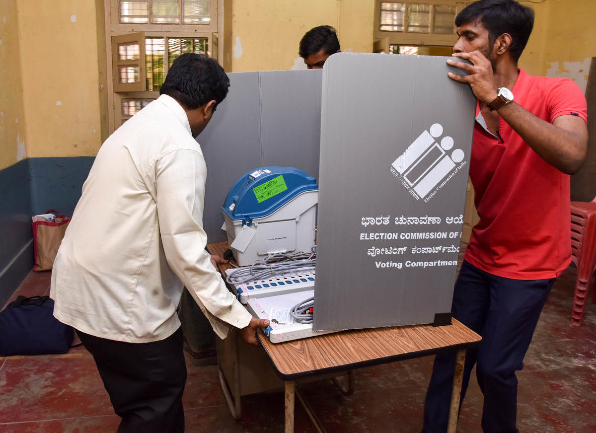 Officials set up a polling booth at a school in Gandhinagar on Wednesday, the eve of general elections in the city. DH PHOTO/B H SHIVAKUMAR