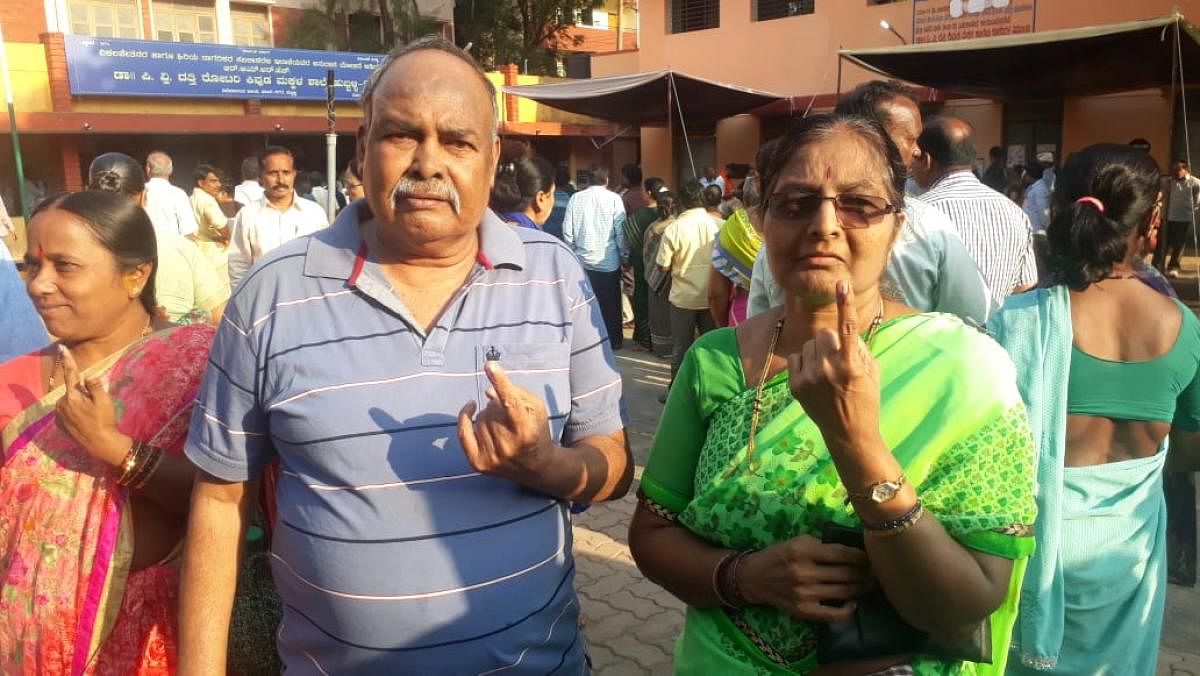 C N Nayak, who lost his mother on Tuesday, along with his wife Indira Nayak, shows the indelible ink mark outside the Bhavani Nagar polling station in Hubballi. DH Photo