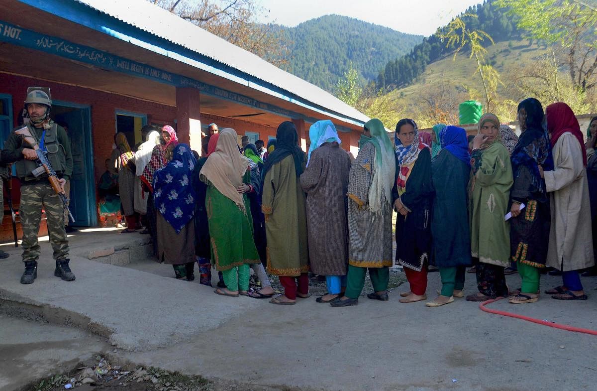 Ananatnag: A security personnel stands guard as voters stand in a queue to cast their votes at a polling station, during the third phase of Lok Sabha elections, in Anantnag district of Jammu and Kashmir, Tuesday, April 23, 2019. (PTI Photo/S. Irfan) (PTI4