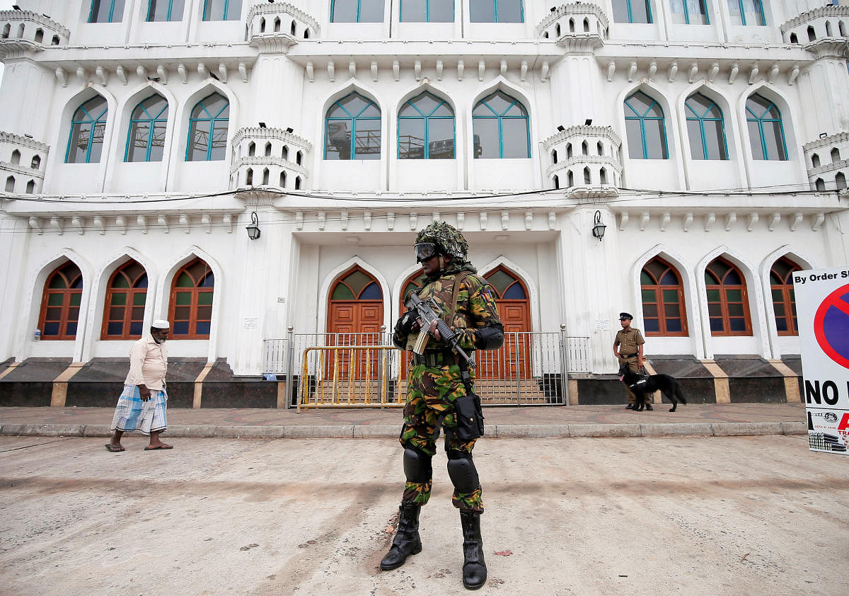 Sri Lankan Special Task Force soldiers stand guard in front of a mosque as a Muslim man walks past him during the Friday prayers at a mosque, days after a string of suicide bomb attacks on Easter Sunday in Colombo. Reuters photo