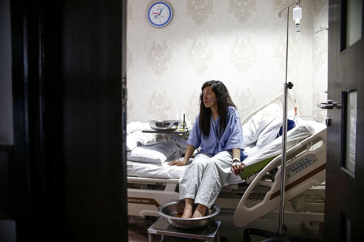 Indian Everest climber Ameesha Chauhan rests on her bed as she dips her frost-bitten feet in a warm solution at a hospital in Kathmandu on May 27, 2019. - Ameesha Chauhan, a survivor of the Everest "traffic jam" who is in hospital recovering from frostbit