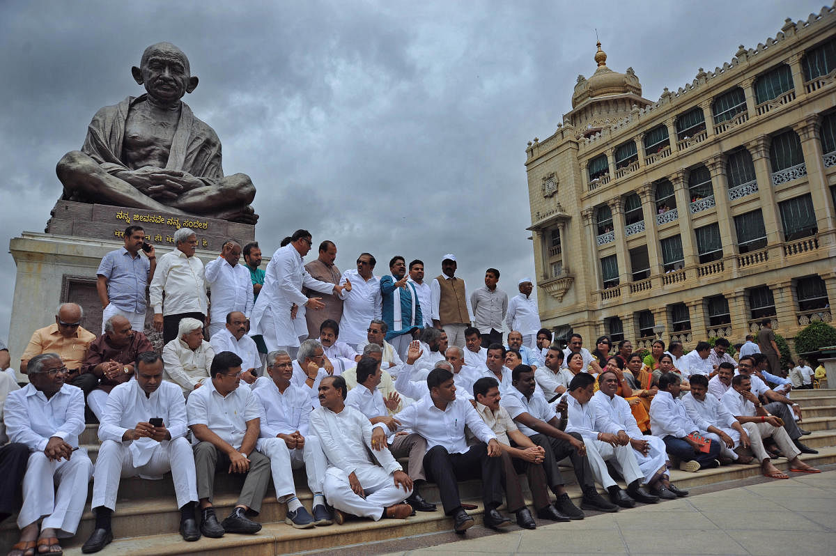 Congress leaders stage a demonstration in frong of the Gandhi statue at Vidhana Soudha, accurding the BJP of attempting to destabilise the government, in Bengaluru on Tuesday. DH Photo