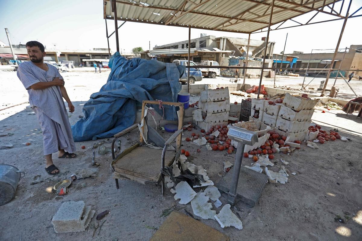 A Syrian vendor stands next to scattered tomatoes following a reported air strike on a market in the town of Saraqeb in the northwestern province of Idlib on July 26, 2019. (Photo by AFP)