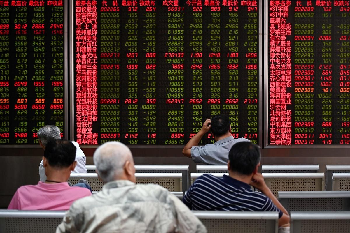 Investors rest on a chair in front of screens showing stock market movements at a securities company in Beijing. (AFP Photo)
