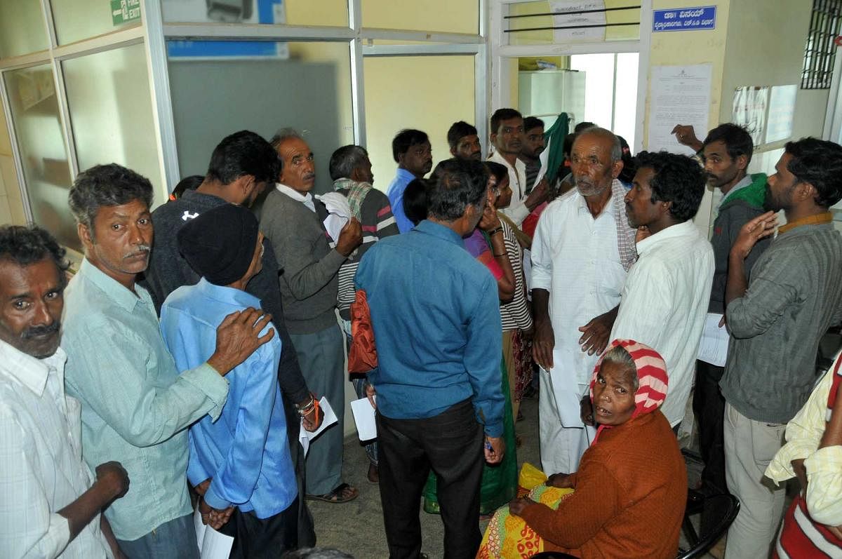 Patients stand in queue for a check-up at the district hospital in Chikkamagaluru on Tuesday.