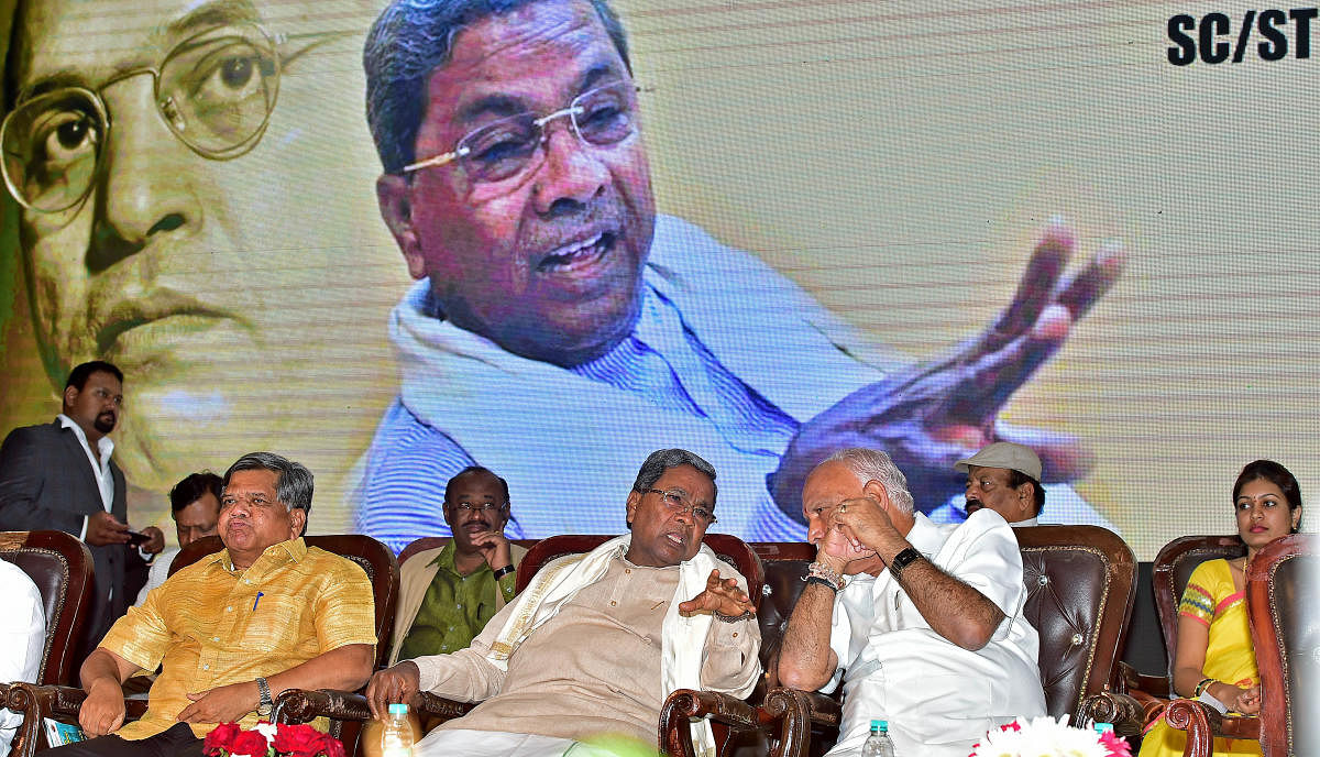 Congress Legislature Party leader Siddaramaiah and Chief Minister B S Yediyurappa share a word at an event to create awareness among Scheduled Castes/Scheduled Tribes industrialists on various incentives they are entitled to, in Bengaluru on Thursday. Med