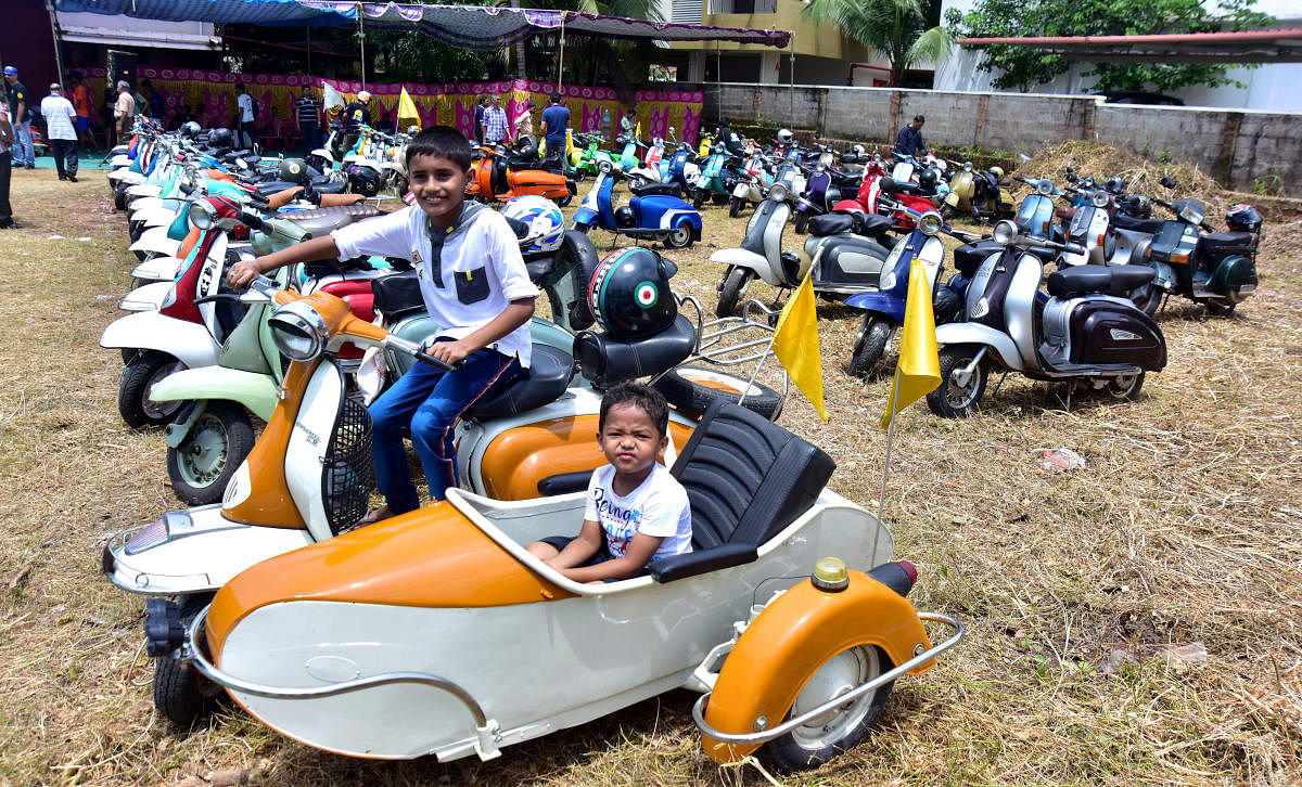Children enjoy sitting on an old scooter exhibited as part of Southern Scooter Meet—a Vintage and Classic Scooter Day, organised by Mangalore Classic Scooter Club, at Alake in Mangaluru on Sunday.