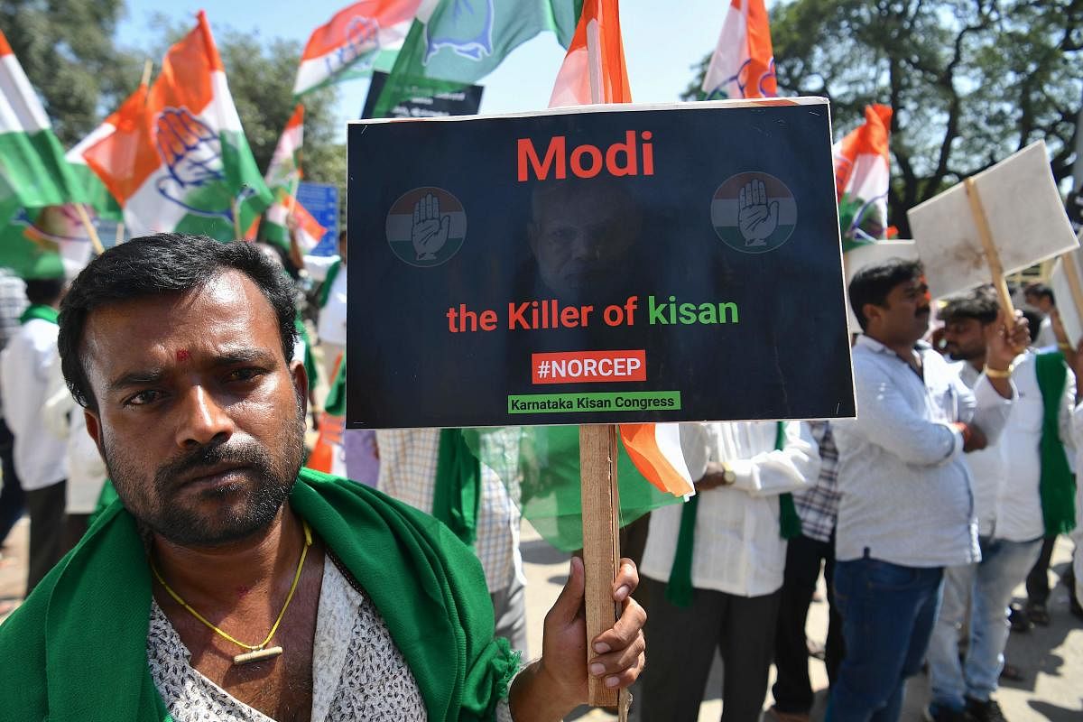 An activist holds a placard during a protest called by Congress party and pro-farmer organisations to condem Narendra Modi led Indian government’s decision to sign the Regional Comprehensive Economic Partnership (RCEP) deal, at the Cantonment Railway Station in Bengaluru on November 4, 2019. (Photo by AFP)