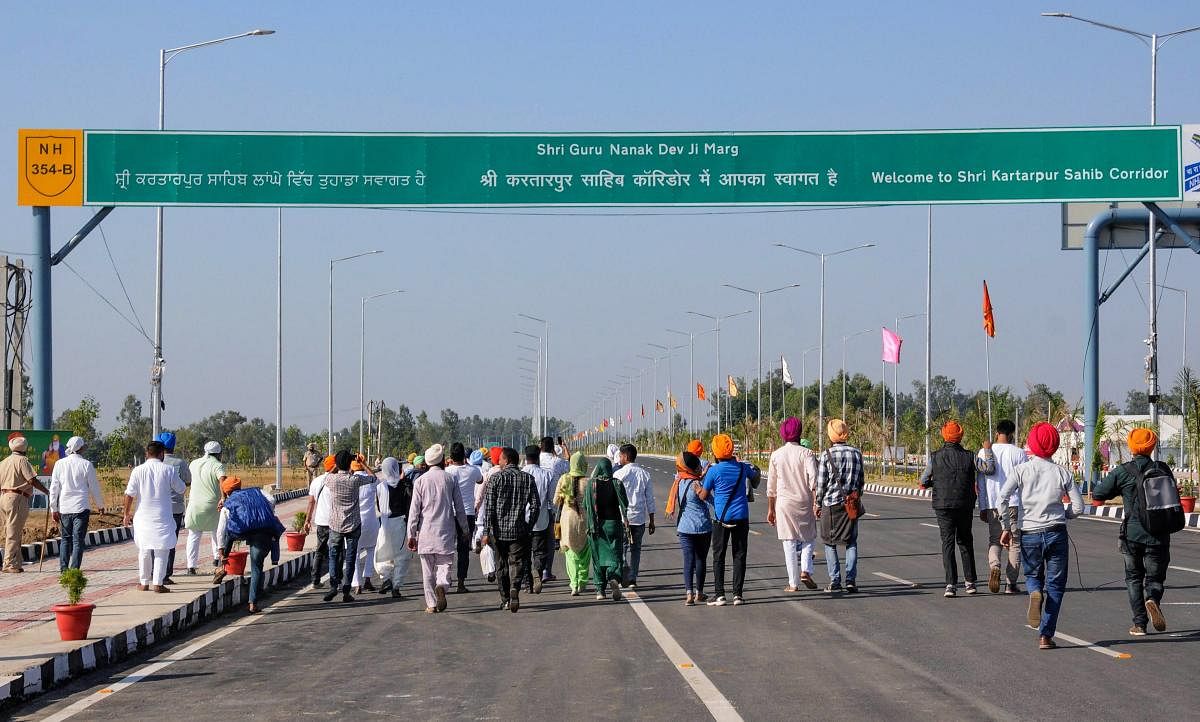 Kartarpur: Sikh devotees stand with folded hands near the zero line as they pay obeisance facing the Kartarpur Sahib Gurdwara in Pakistan on the day of the inauguration of the Kartarpur corridor at Dera Baba Nanak. (PTI Photo)