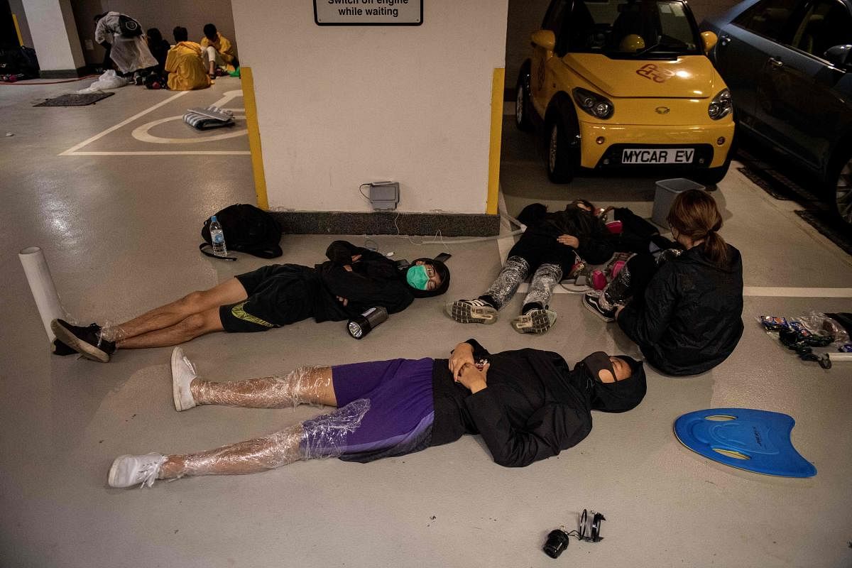 Protesters sleep on the floor of a parking lot inside the Hong Kong Polytechnic University in the Hung Hom district of Hong Kong. (Photo by Reuters)