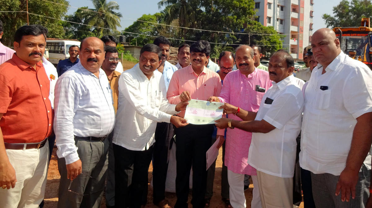 Deputy Commissioner G Jagadeesha hands over trip sheet to a lorry owner who had registered online for sand transportation at Hiriyadka sand stockyard in Udupi.