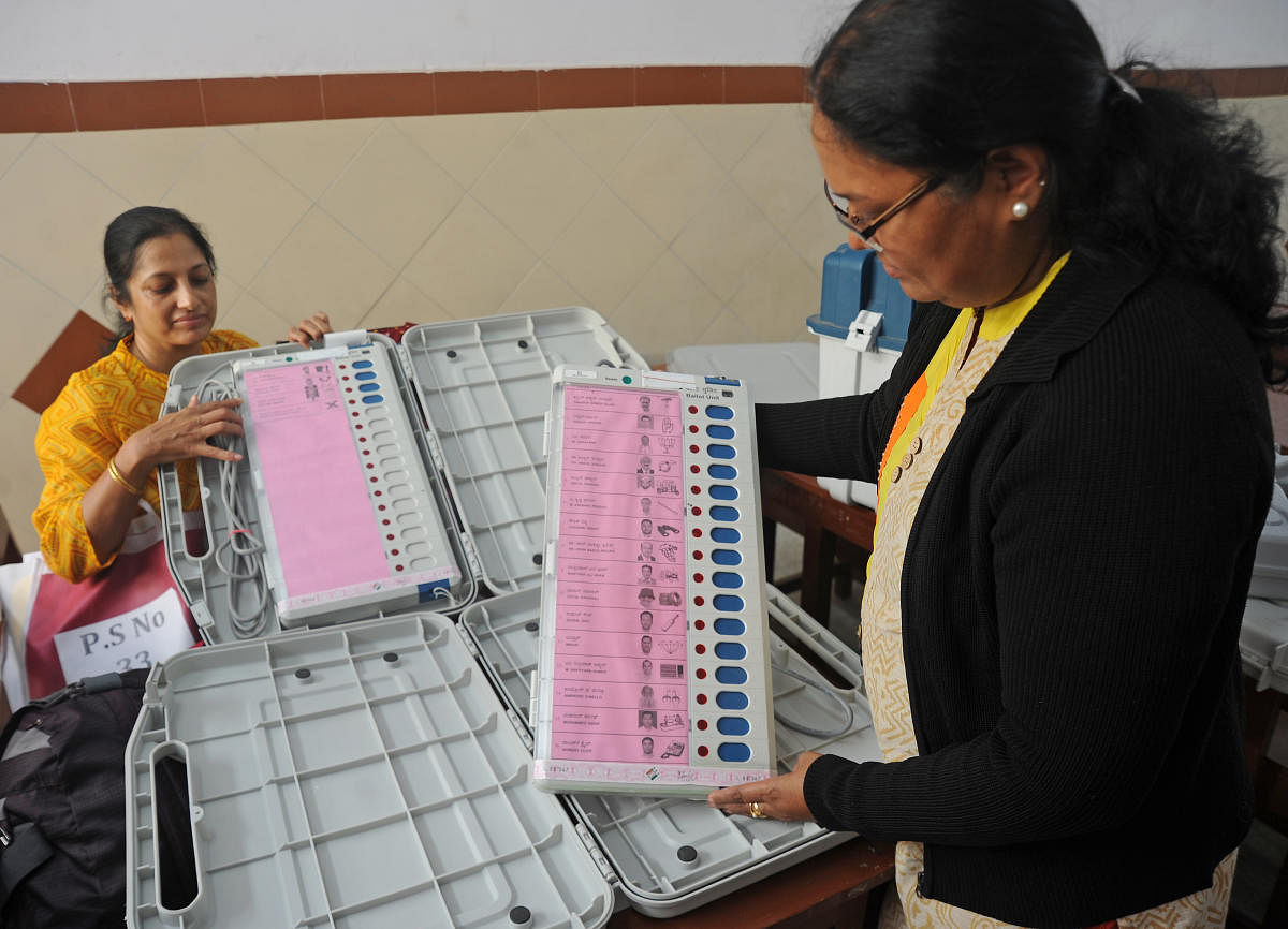 Election staff check the EVMs at a polling booth in Bengaluru on Wednesday. DH Photo