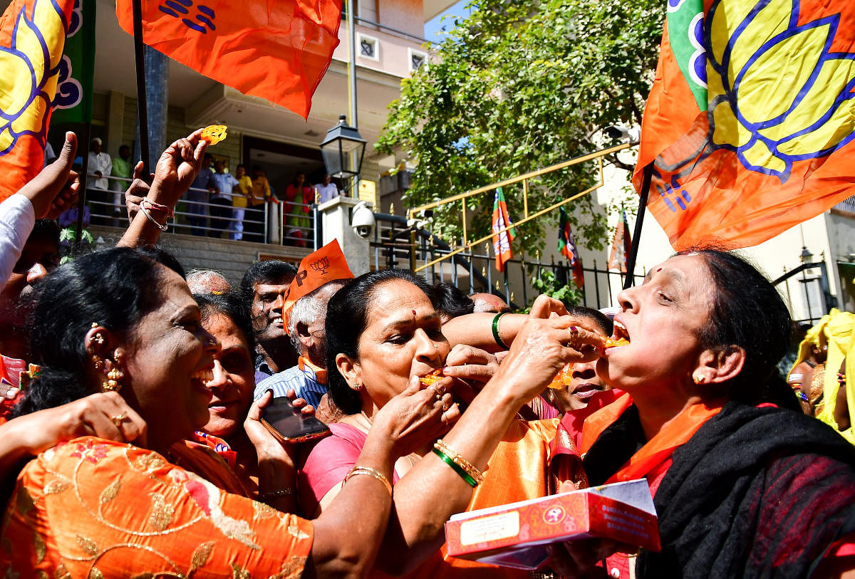 BJP supporters distribute sweets and burst firecrackers near the party’s state headquarters in Malleswaram to celebrate its victoryin the assembly bypolls on Monday. (DH photo)