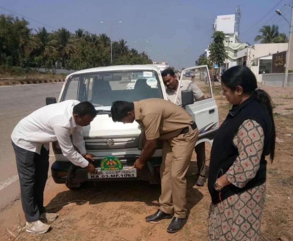 Transport department officials, led by Mysuru (East) RTO K S Soundarya, remove a defective number plate from a vehicle, in Mysuru. pic by special arrangement