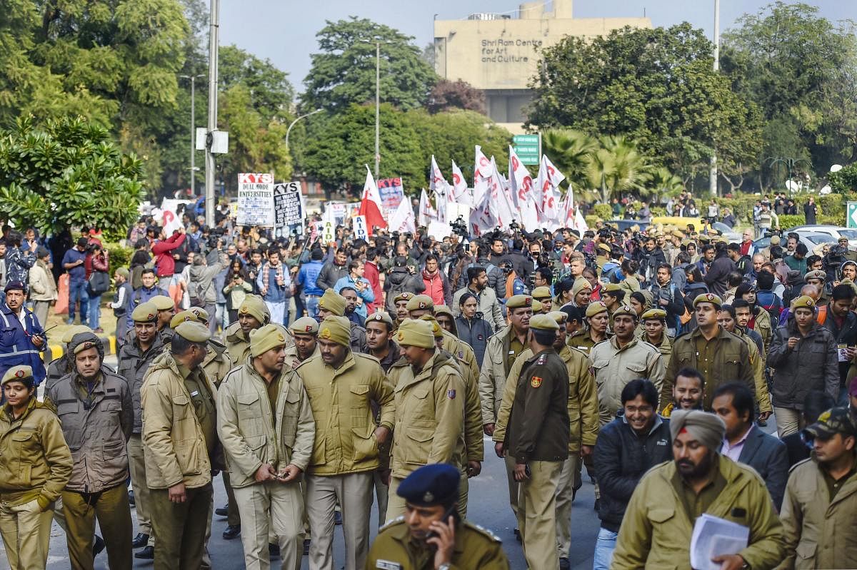 Police personnel walk in front of JNU students' protest march from Mandi House to HRD Ministry, demanding removal of the university vice-chancellor, at Ferozeshah Road in New Delhi, Thursday, Jan. 9, 2020. (PTI Photo)