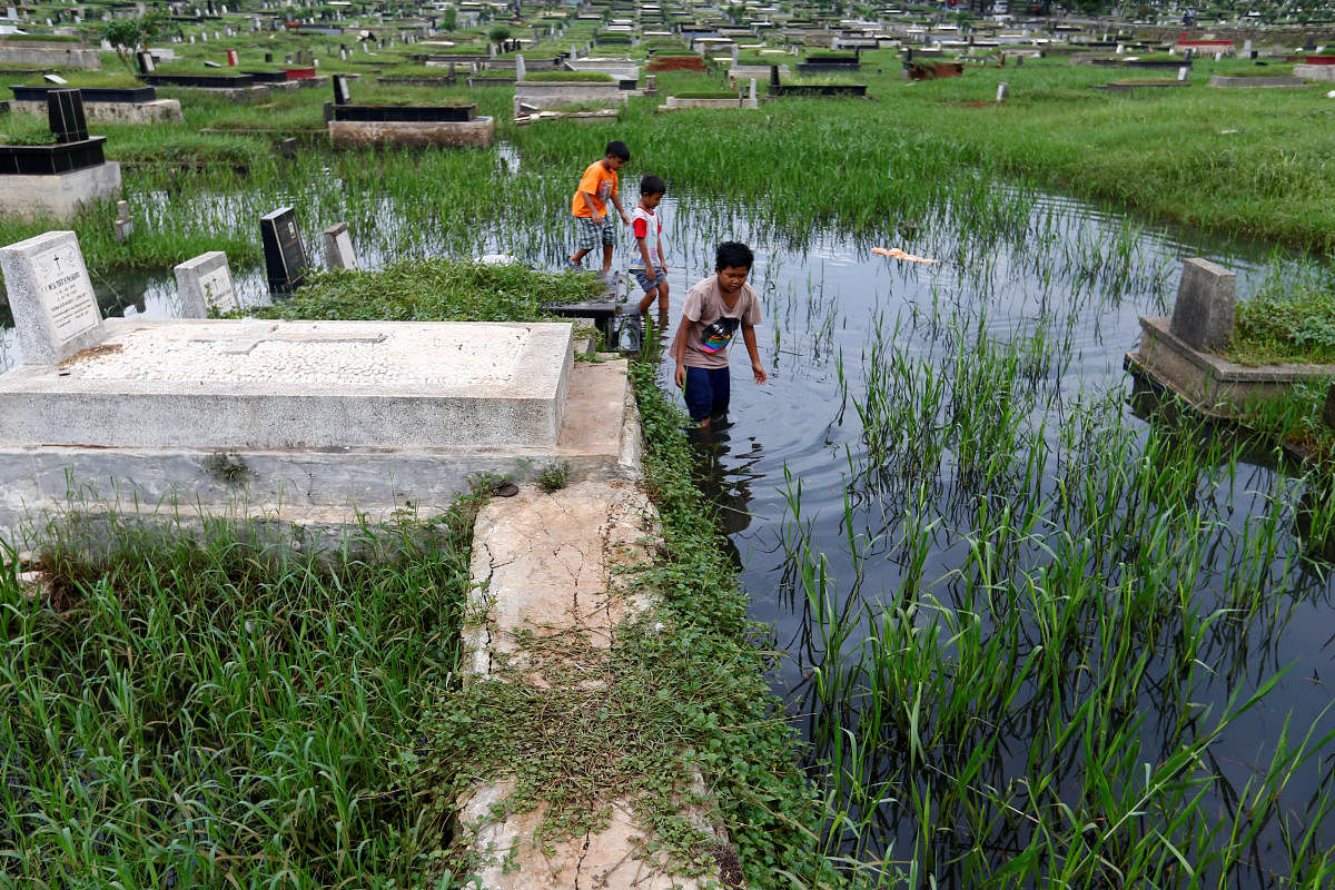 Children play at a flooded cemetery complex in Jakarta, Indonesia. (Reuters Photo)