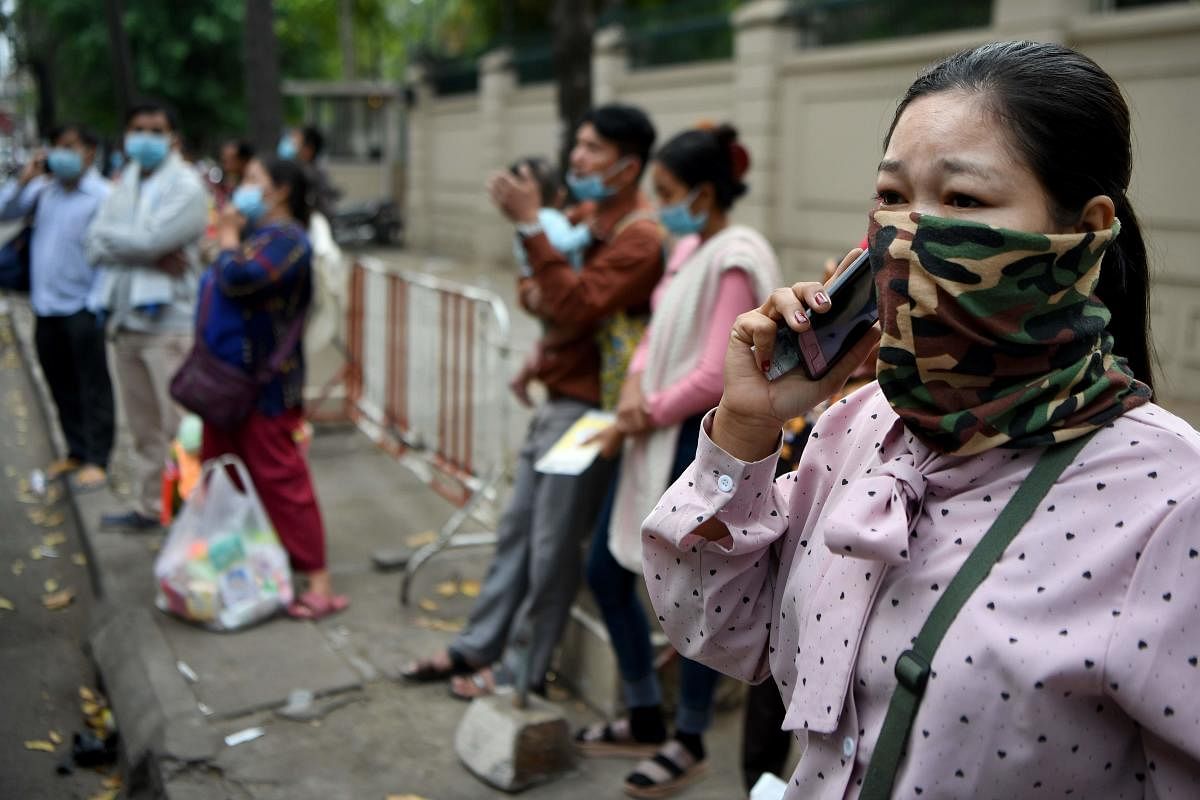People wear face masks as they stand in front of a children's hospital in Phnom Penh on January 30, 2020, after the first case of novel coronavirus was reported in the country. (AFP Photo)