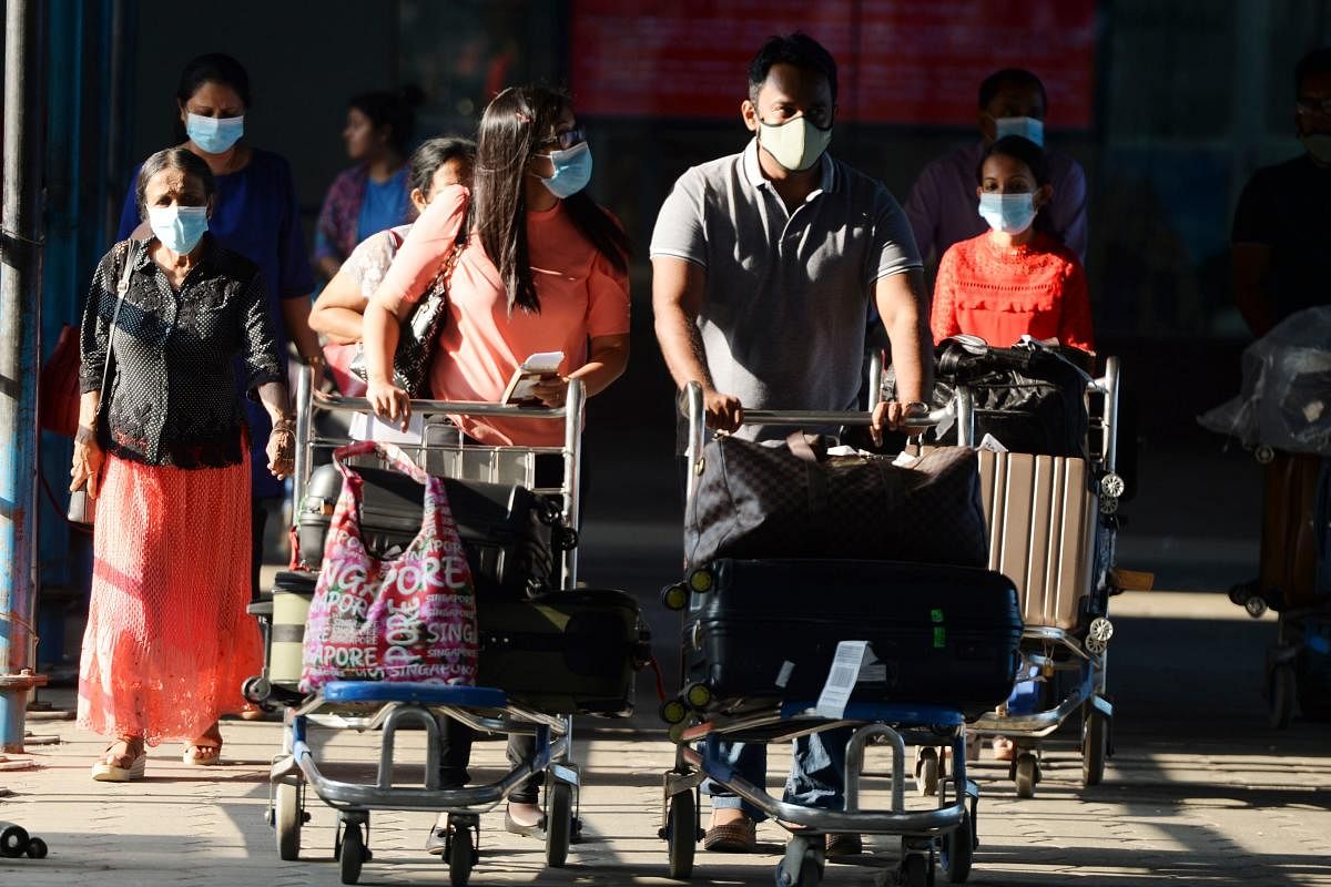 Arriving passengers wearing face masks as prevention for the SARS-like virus outbreak which began in the Chinese city of Wuhan, push trolleys with their luggage at Anna International airport in Chennai on January 31, 2020. (AFP Photo)