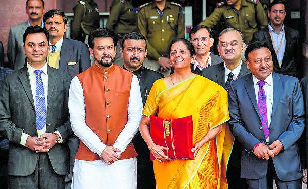 Union Finance Minister Nirmala Sitharaman, holding a folder containing the Union Budget documents, poses for photographers along with her deputy Anurag Thakur and a team of officials, outside the Ministry of Finance, North Block in New Delhi, Saturday, Feb. 1, 2020. (PTI Photo/Kamal Singh) 