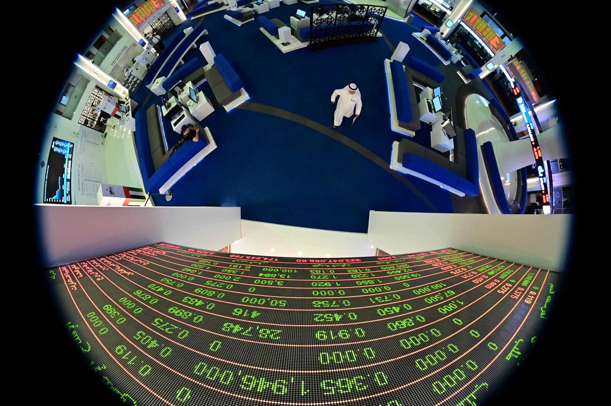 A picture taken with a fisheye lense shows traders walking by beneath a stock display board at the Dubai Stock Exchange in the United Arab Emirates, on March 8, 2020. (AFP Photo)