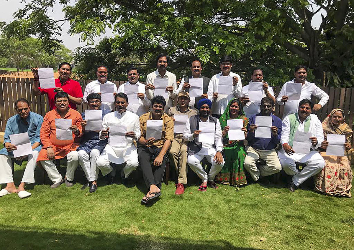 The MLAs of the ruling Congress in Madhya Pradesh show their resignation letters as they pose for a group photo, in Bengaluru on Tuesday. PTI Photo