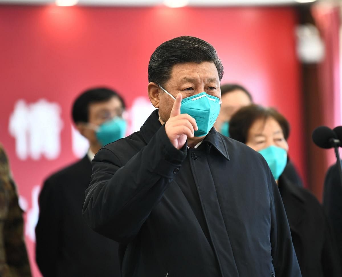 This photo released on March 10, 2020 by China's Xinhua News Agency shows Chinese President Xi Jinping wearing a mask as he GESTURES to a coronavirus patient and medical staff via a video link at the Huoshenshan hospital in Wuhan, in China's central Hubei province on March 10, 2020. (Photo by AFP)