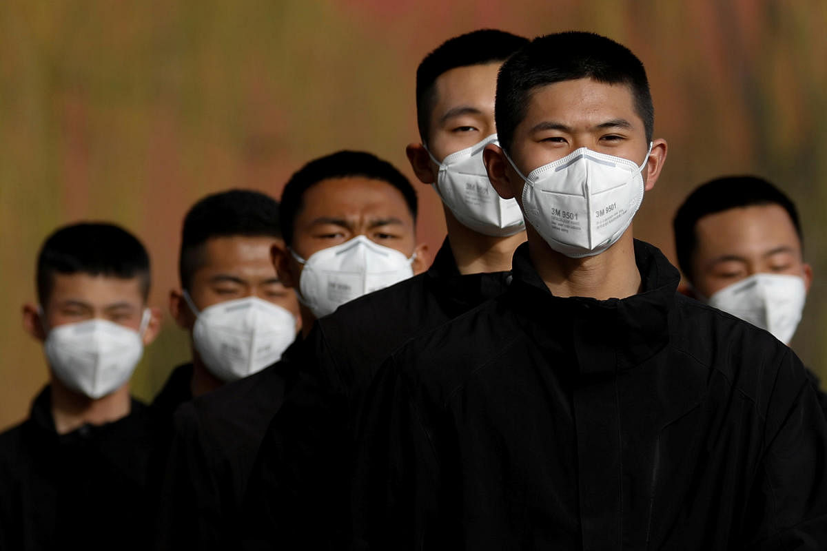 Security personnel wearing face masks to contain the spread of coronavirus disease (COVID-19) walk along a street outside Forbidden City in Beijing, China. (REUTERS Photo)