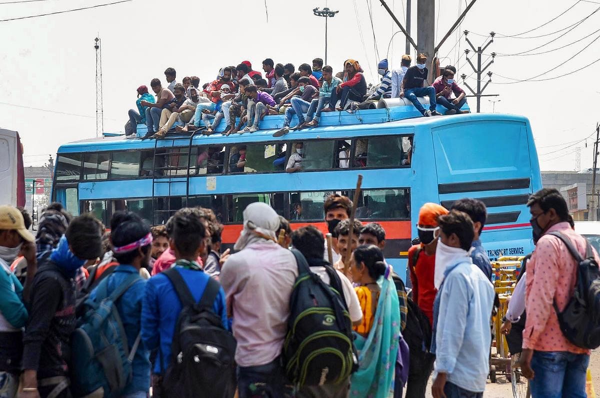 Passengers who have arrived from different states, board a crowded bus during locked down amid the coronavirus pandemic, at Mithapur bus stand, in Patna. (PTI Photo)