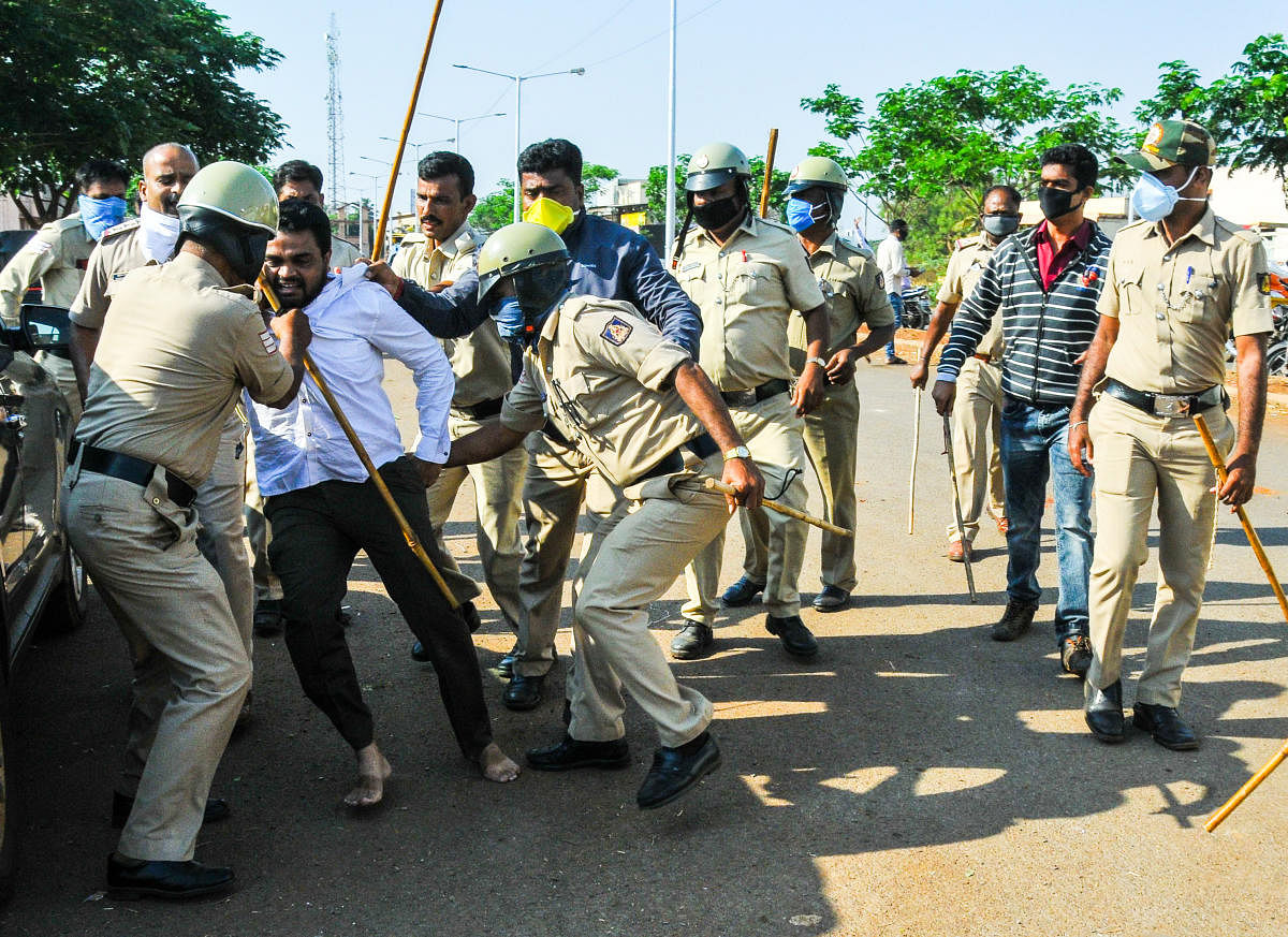 Police forcibly shift a youth while dispersing crowd at the wholesale vegetable market at the APMC yard in Hubballi on Friday. DH photo