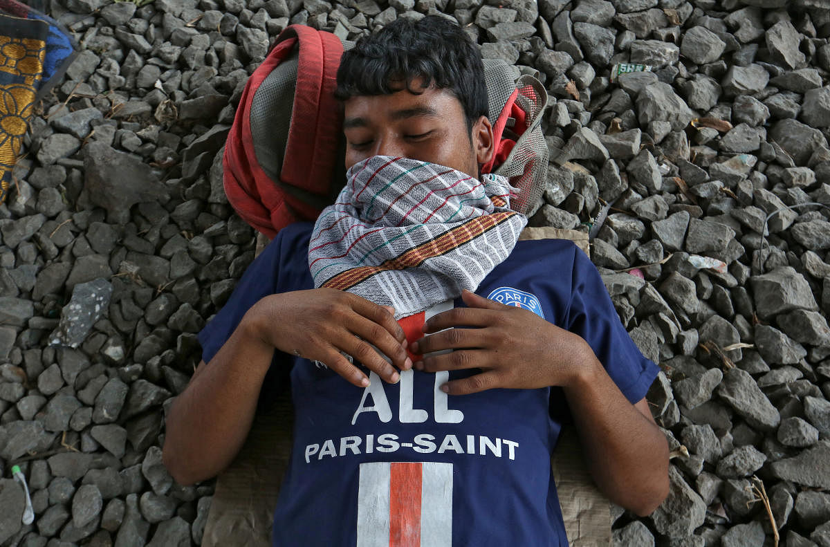 A migrant worker wearing a handkerchief as a mask sleeps next to a railway track during a 21-day nationwide lockdown to slow the spreading of coronavirus disease (COVID-19) in in Mumbai, India, April 2, 2020. REUTERS/Prashant Waydande