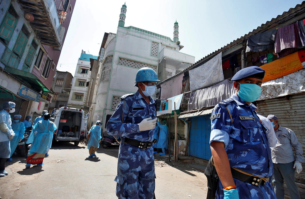 Rapid Action Force officers wearing protective masks walk past a mosque from where dozens of men, who according to health and police officials had visited three Muslim missionary gatherings including in Nizamuddin area of New Delhi, were taken to a quaran