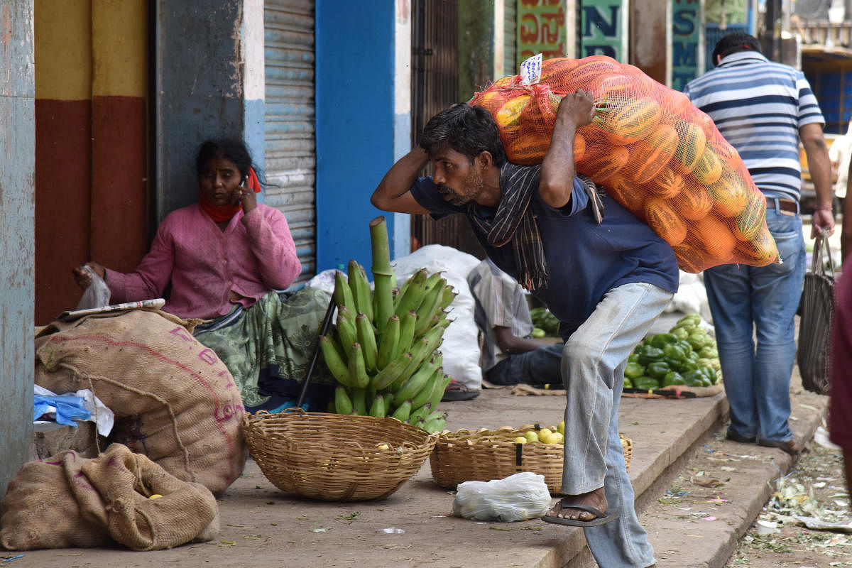 Worker downloading vegetables form a goods carrier due to caronavirus, Covid-19 lockdown vegetables came rarely at Kalasipalya market in Bengaluru. (Photo by S K Dinesh)