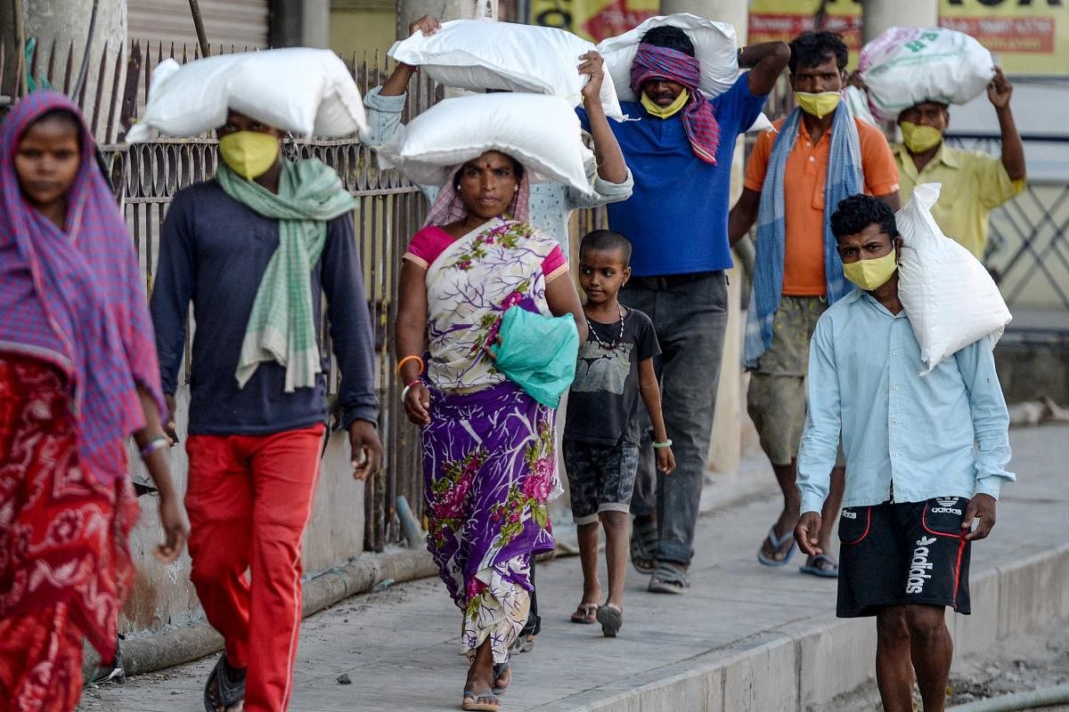Migrant workers carrying sacks of groceries distributed at their workplace walk on a street during a government-imposed nationwide lockdown. AFP