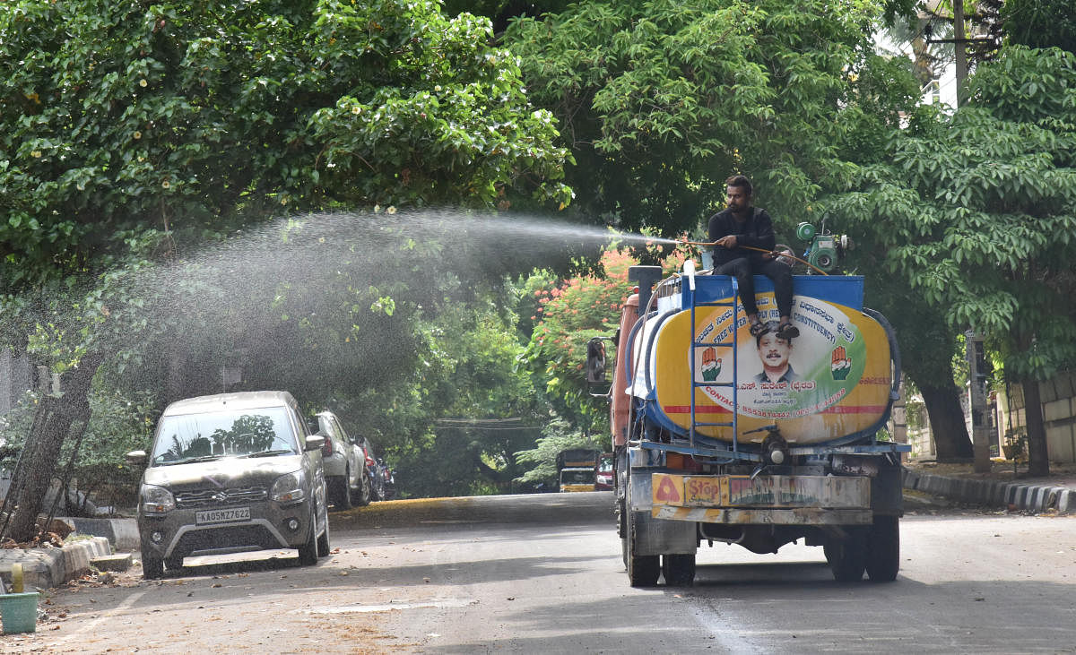A worker sprays disinfectant on a road at Sanjaynagar in Bengaluru on Tuesday. DH Photo/Janardhan B K