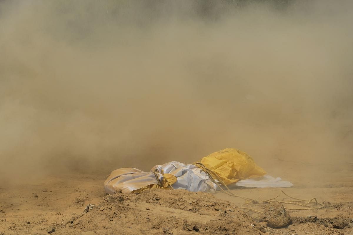 Dust covers the dead body of a woman, who died from the COVID-19 coronavirus disease, before her burial at a graveyard in New Delhi on April 16, 2020. (Photo by SAJJAD HUSSAIN / AFP)