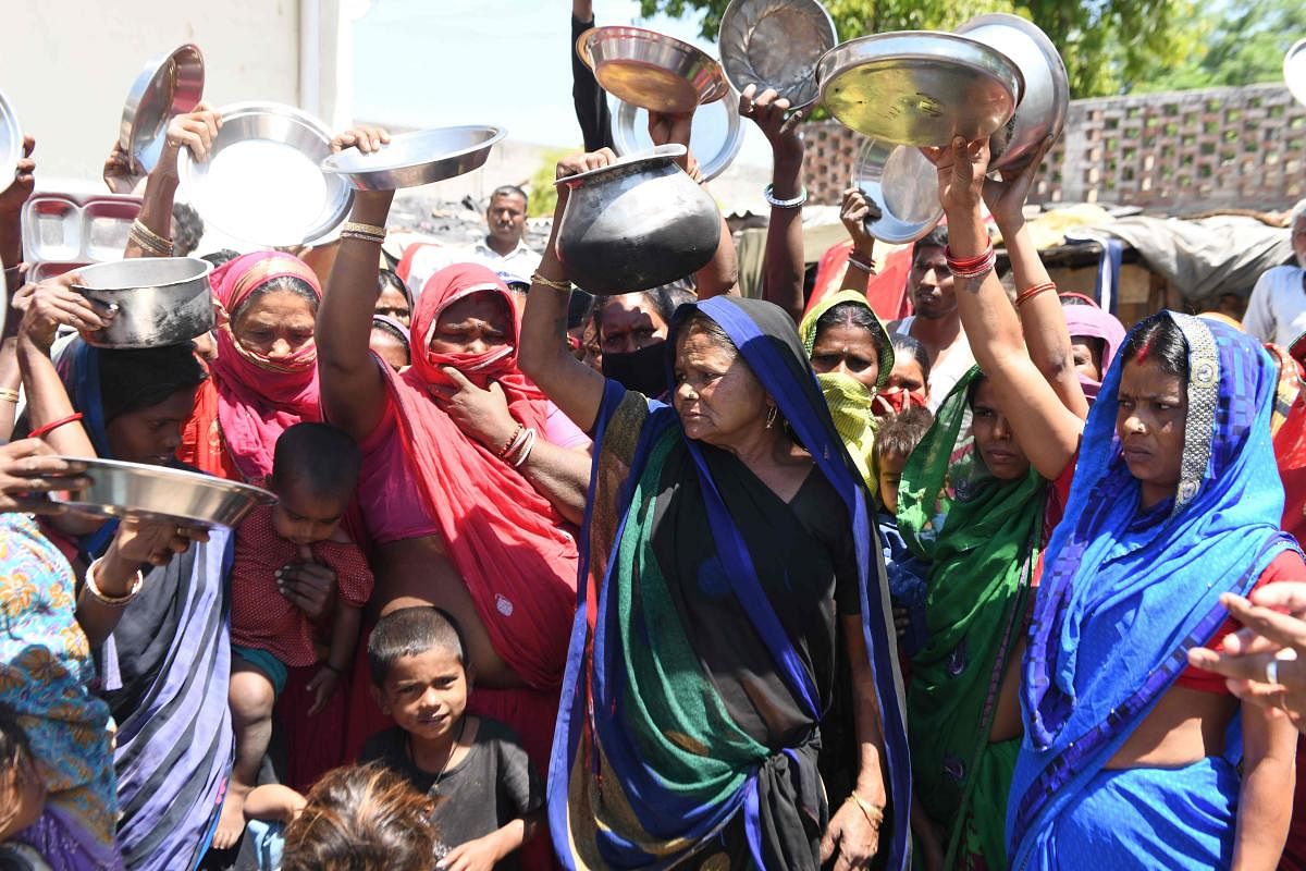 Migrant labourers and families from Bihar and Uttar Pradesh states hold kitchen utensils as they protest against the government for the lack of food at a slum area during a government-imposed nationwide lockdown as a preventive measure against the COVID-1
