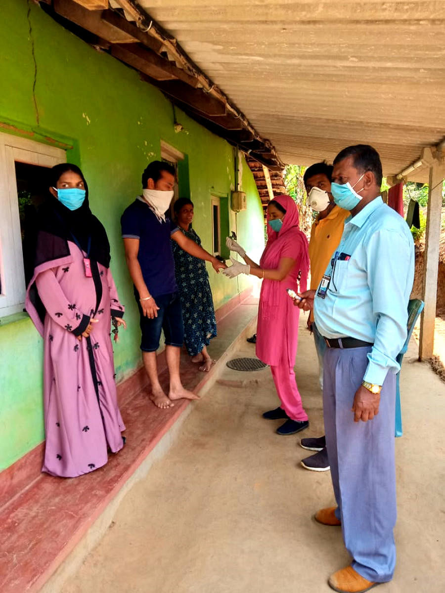 Members of Appashettalli Gram Panchayat Task Force Committee apply quarantine seal on the hand of the youth who had come from Mysuru to Shanivarasanthe.