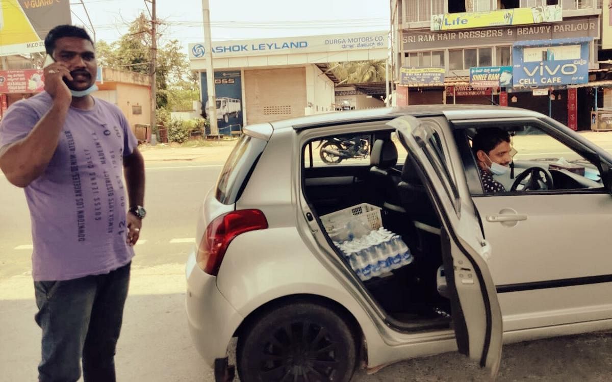 Samad from Ullal and Yasir Angaragundi from Baikampady (seated inside the car) distribute packaged mineral water to thirsty people.