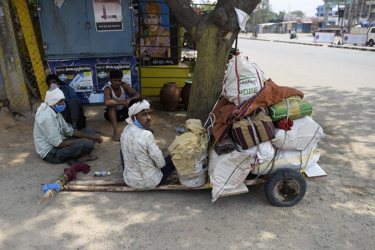 Migrant workers from the Indian state of Maharashtra rest under the shade next to a cart loaded with their belongings while walking along a National Highway 44 to reach their hometowns during a government-imposed nationwide lockdown as a preventive measur