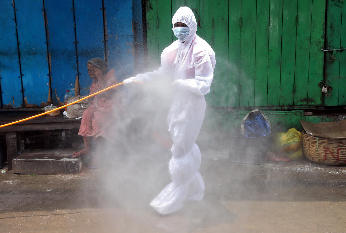 A municipal worker wearing a protective gear sprays disinfectant at a market area during an extended nationwide lockdown to slow the spreading of the coronavirus disease (COVID-19), in Kolkata. (REUTERS Photo)